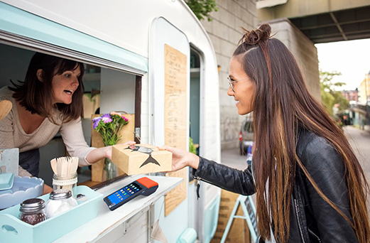 The food truck owner efficiently processes payments using a handheld POS system.